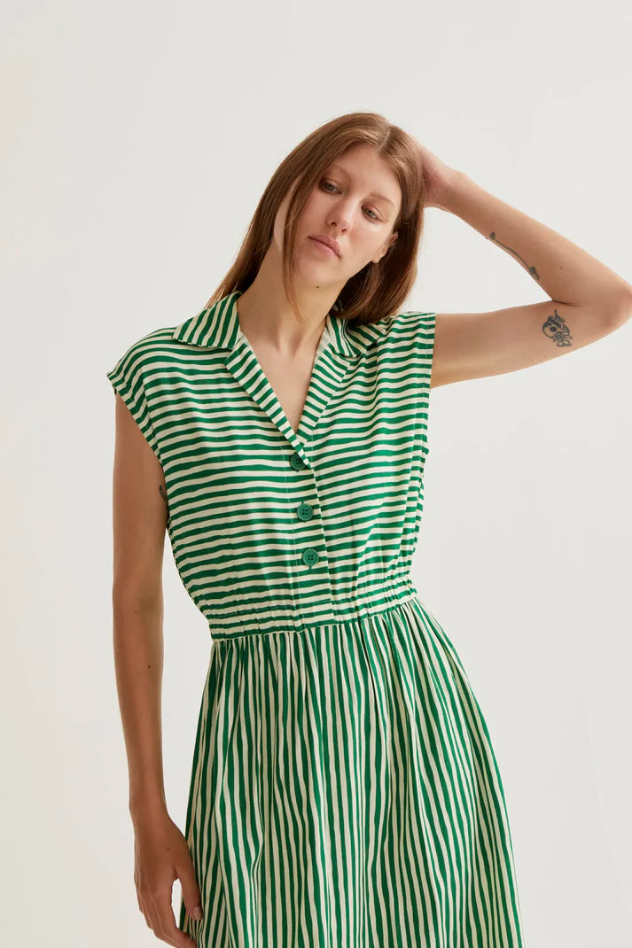 Woman wearing a green and white striped dress against a plain background