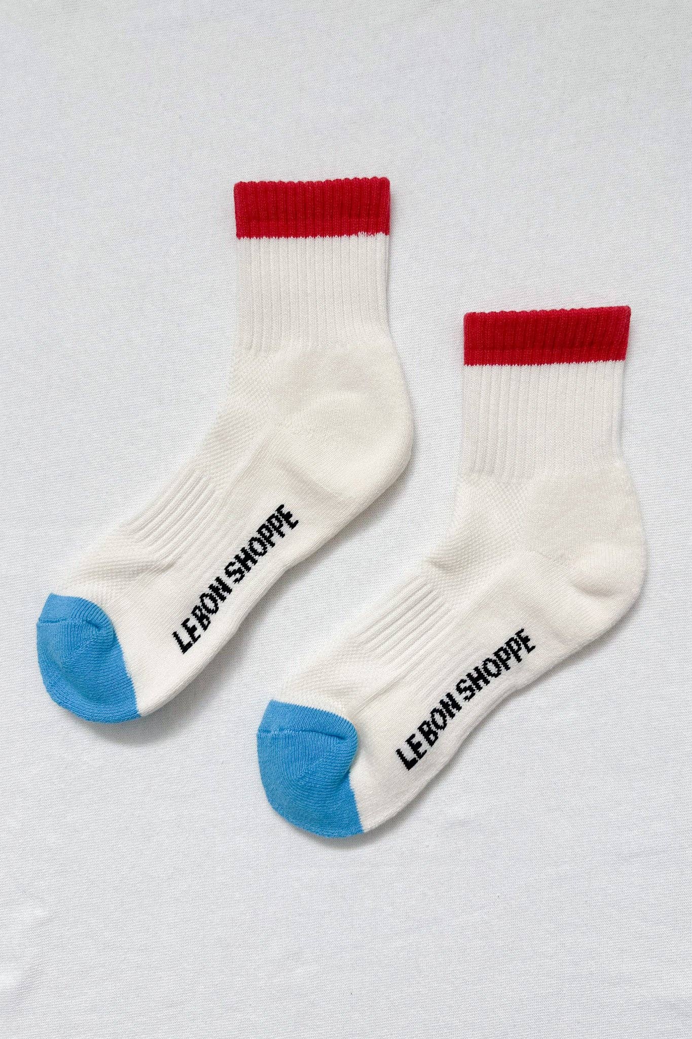 Two white socks with red and blue accents on a light gray background