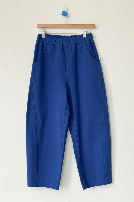 Blue pants hanging on a wooden hanger against a white background