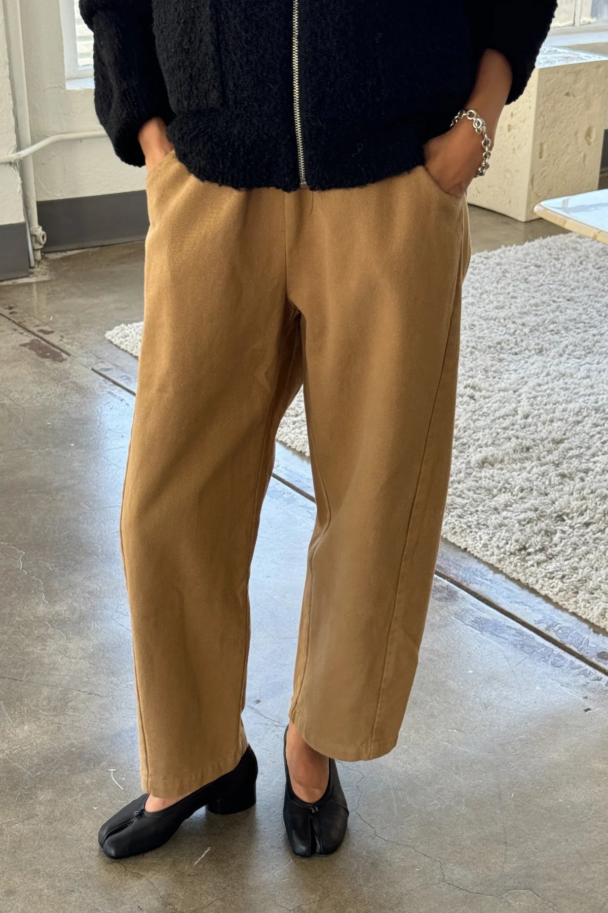 Person wearing beige pants and black shoes indoors.