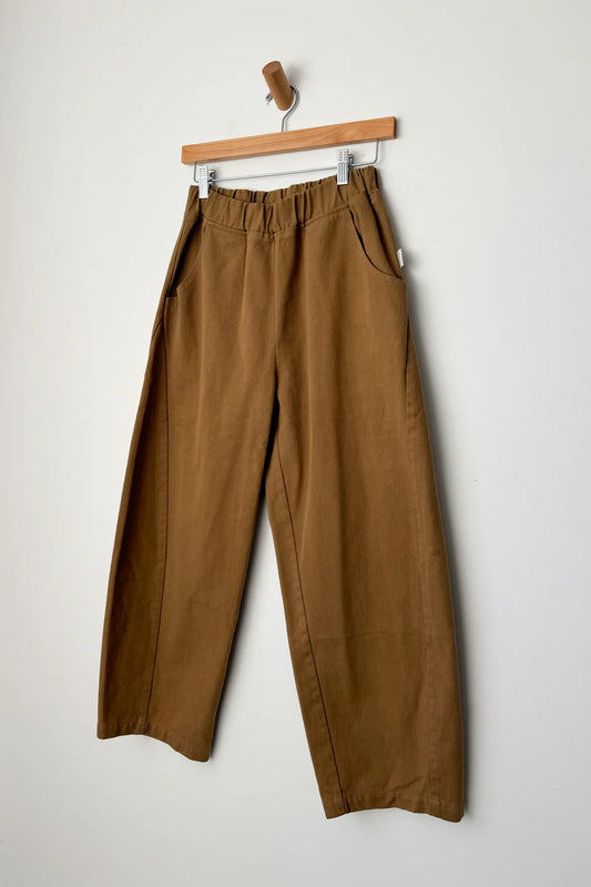 Brown pants hanging on a wooden hanger against a white background