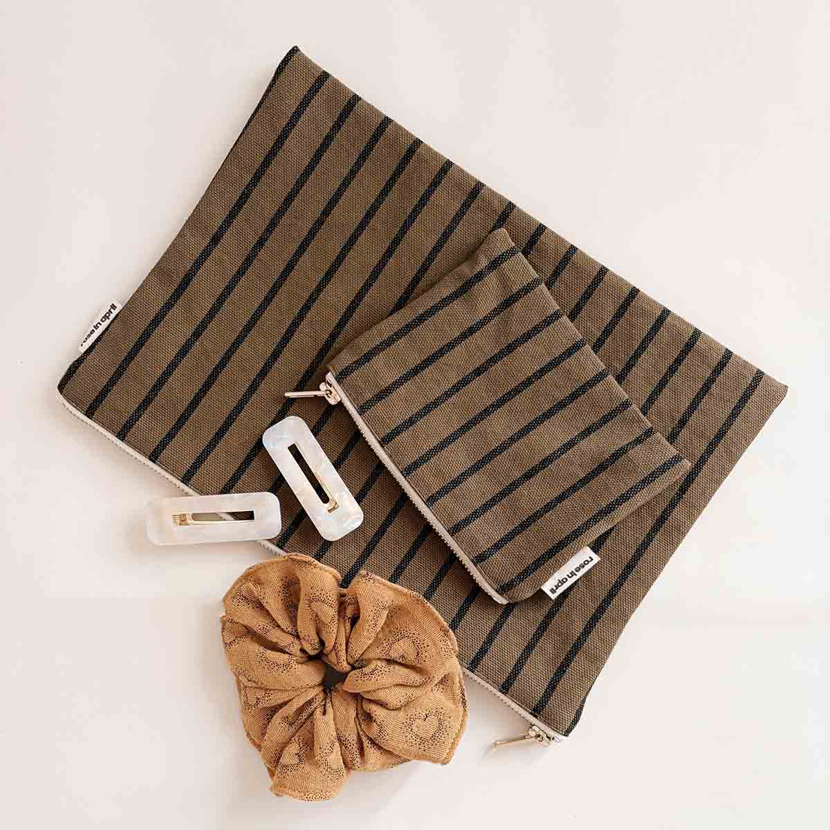 Brown striped pouch with hair accessories on a light beige background