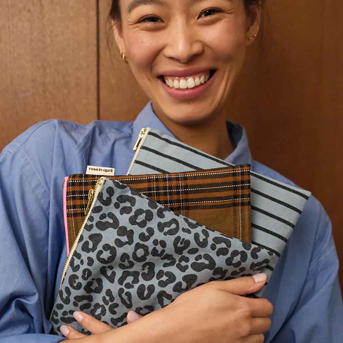 Person holding three patterned bags against a brown background