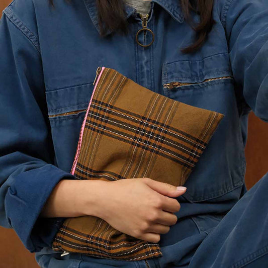 Person holding a brown plaid bag with a blue jacket