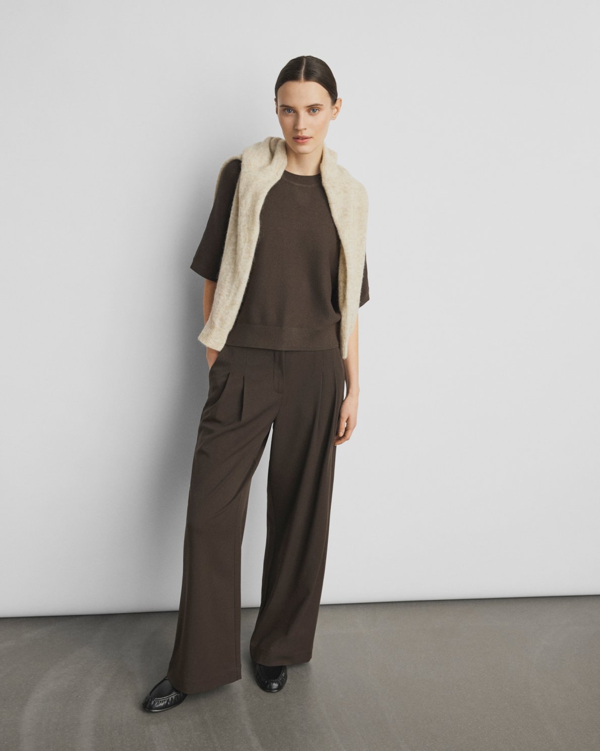 Woman wearing a brown outfit with a beige vest against a white background