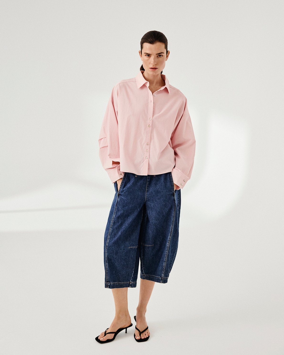 Person wearing a pink shirt and blue jeans on a white background