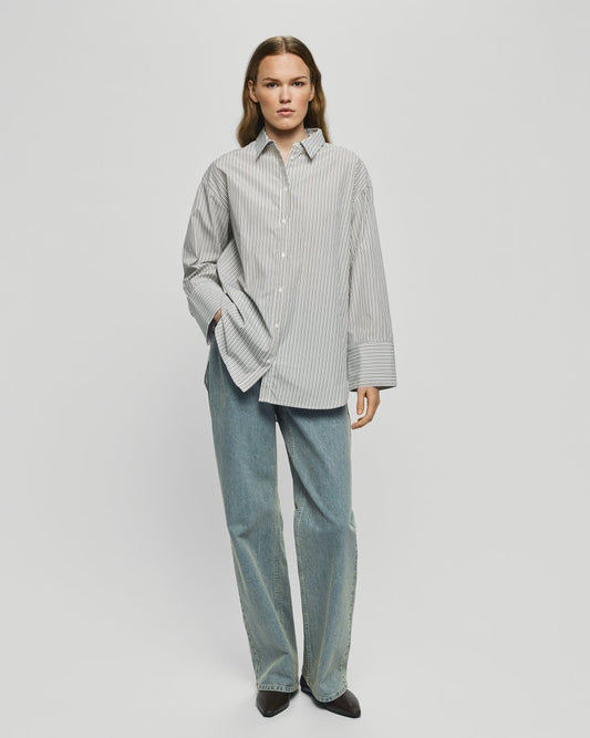 woman wearing a stripe long sleeve shirt and blue jeans on a neutral background