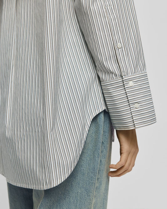 Striped shirt cuff and blue jeans on a light gray background