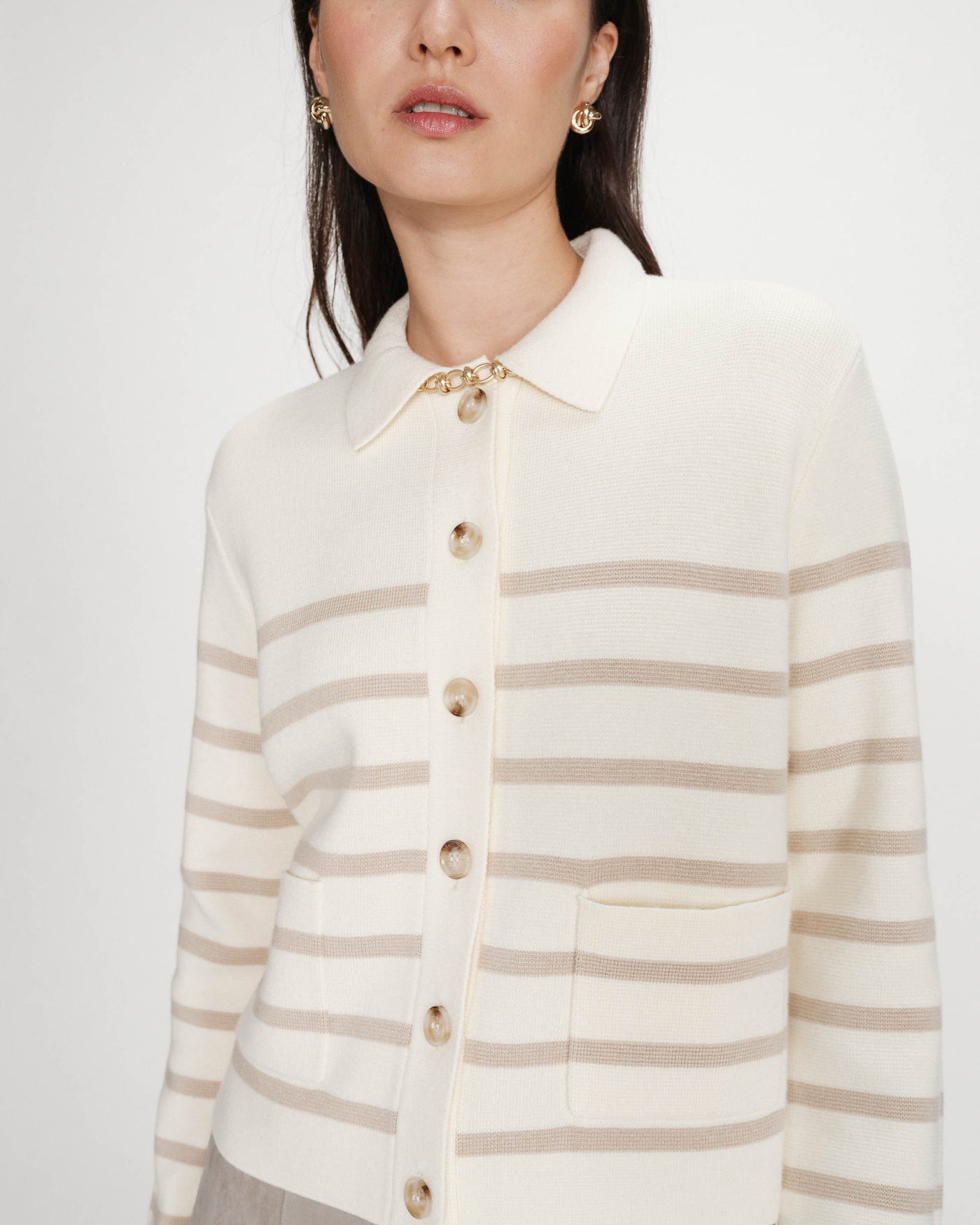 Woman wearing a cream and beige striped cardigan on a white background