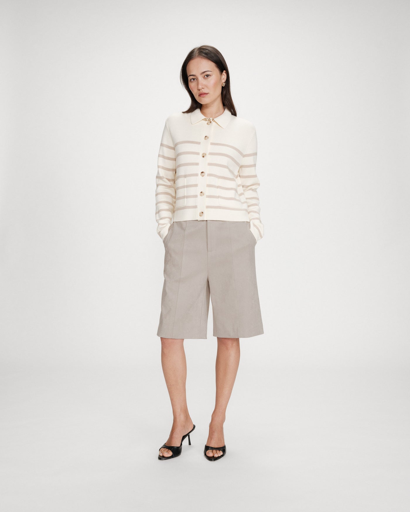 Woman wearing a striped sweater and beige skirt on a white background