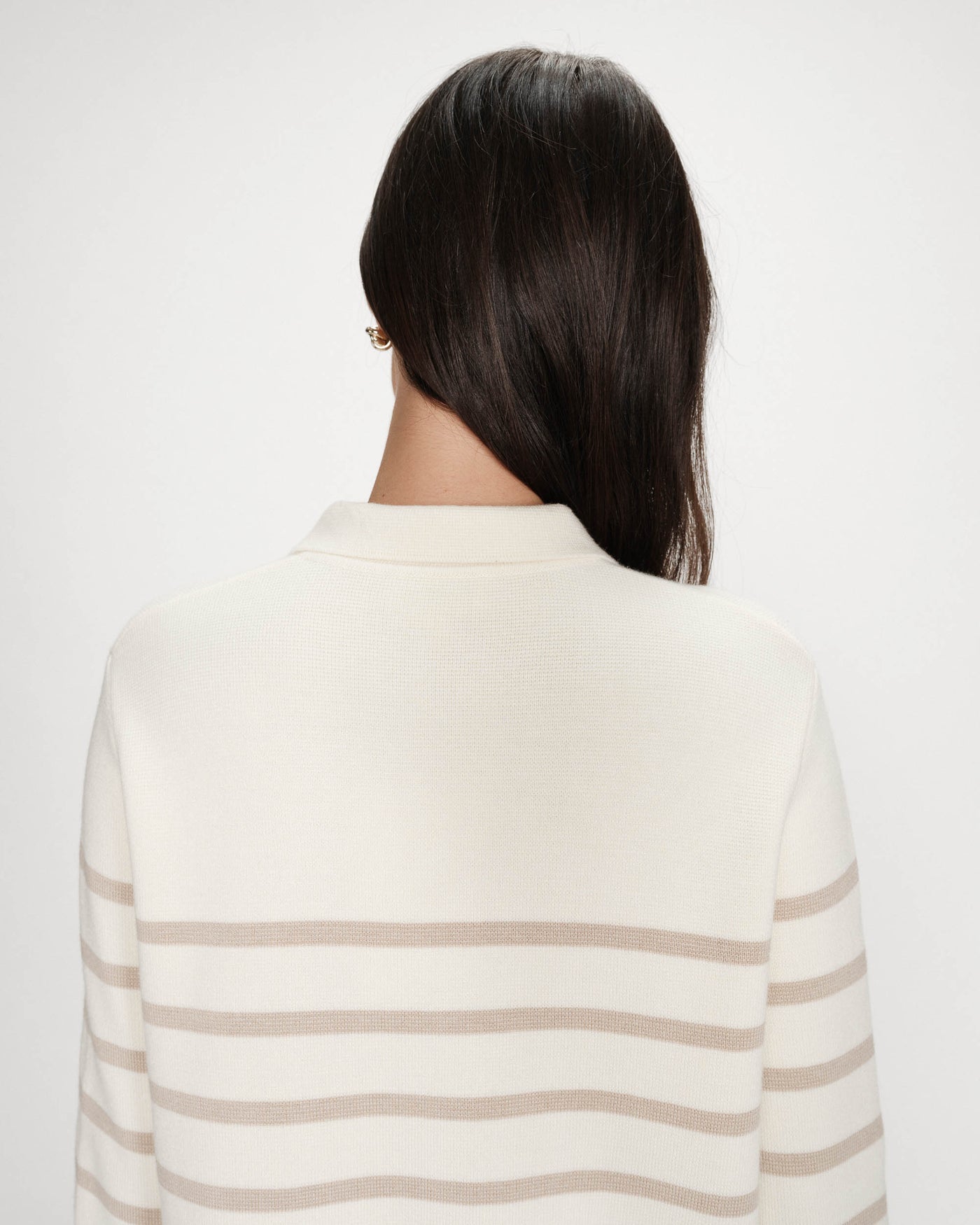 Person wearing a cream and beige striped sweater on a white background