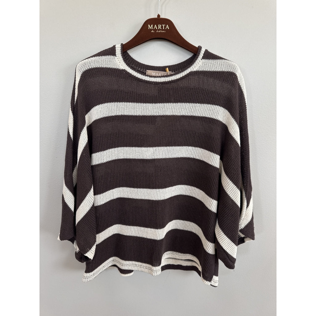 A dark brown and off-white horizontally striped knit sweater hanging on a wooden hanger branded 'MARTA', set against a plain light gray wall.