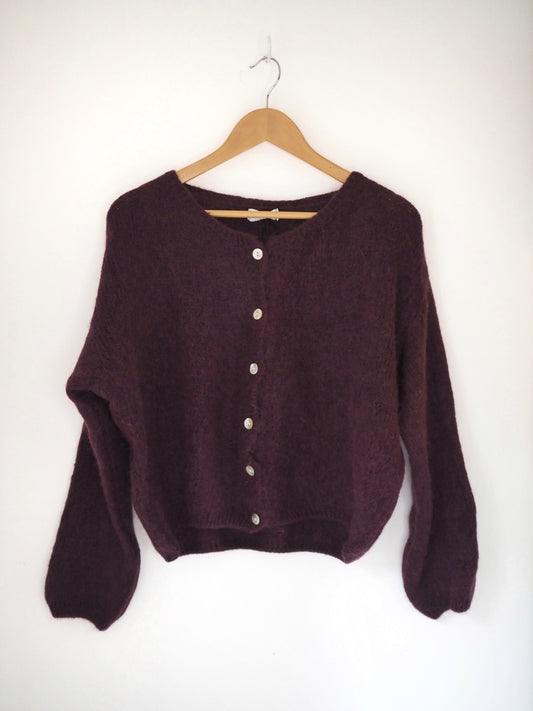 Maroon sweater on a wooden hanger against a white background