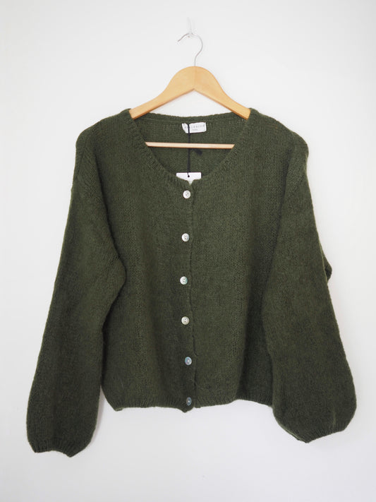 Green cardigan on a wooden hanger against a white background