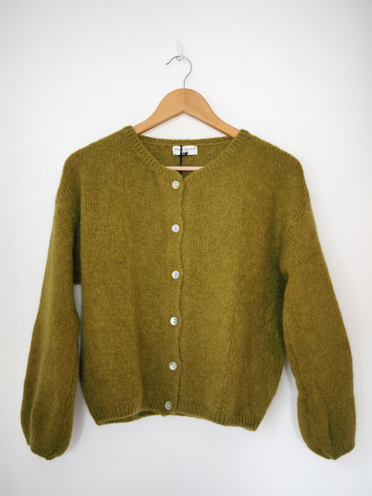 Green cardigan on a wooden hanger against a white background