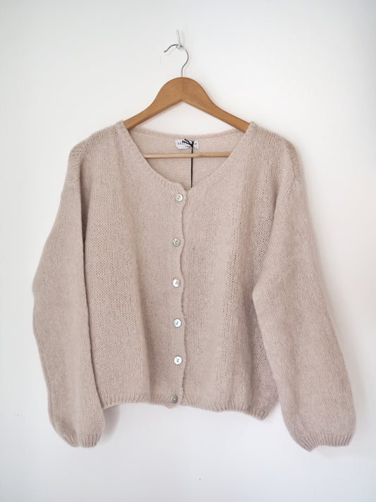Beige cardigan on a wooden hanger against a white background