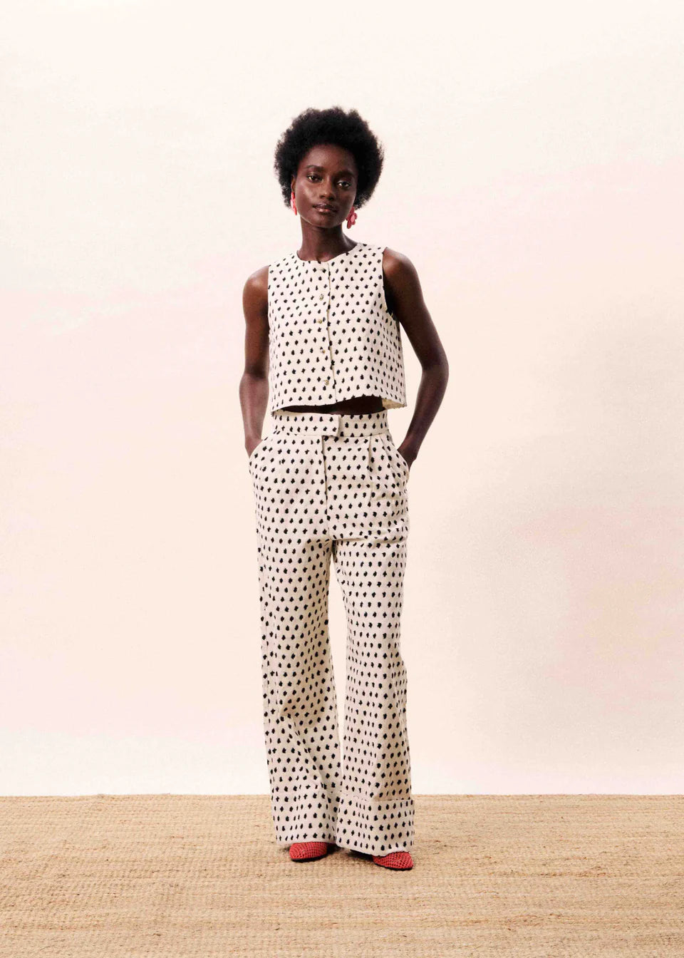 Person wearing a polka dot sleeveless top and wide-leg pants on a plain background