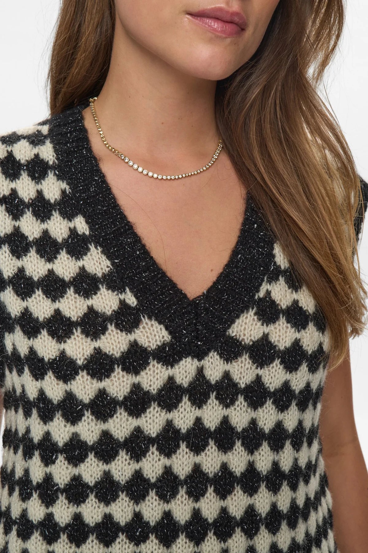 Black and white patterned sleeveless top worn by a person on a white background