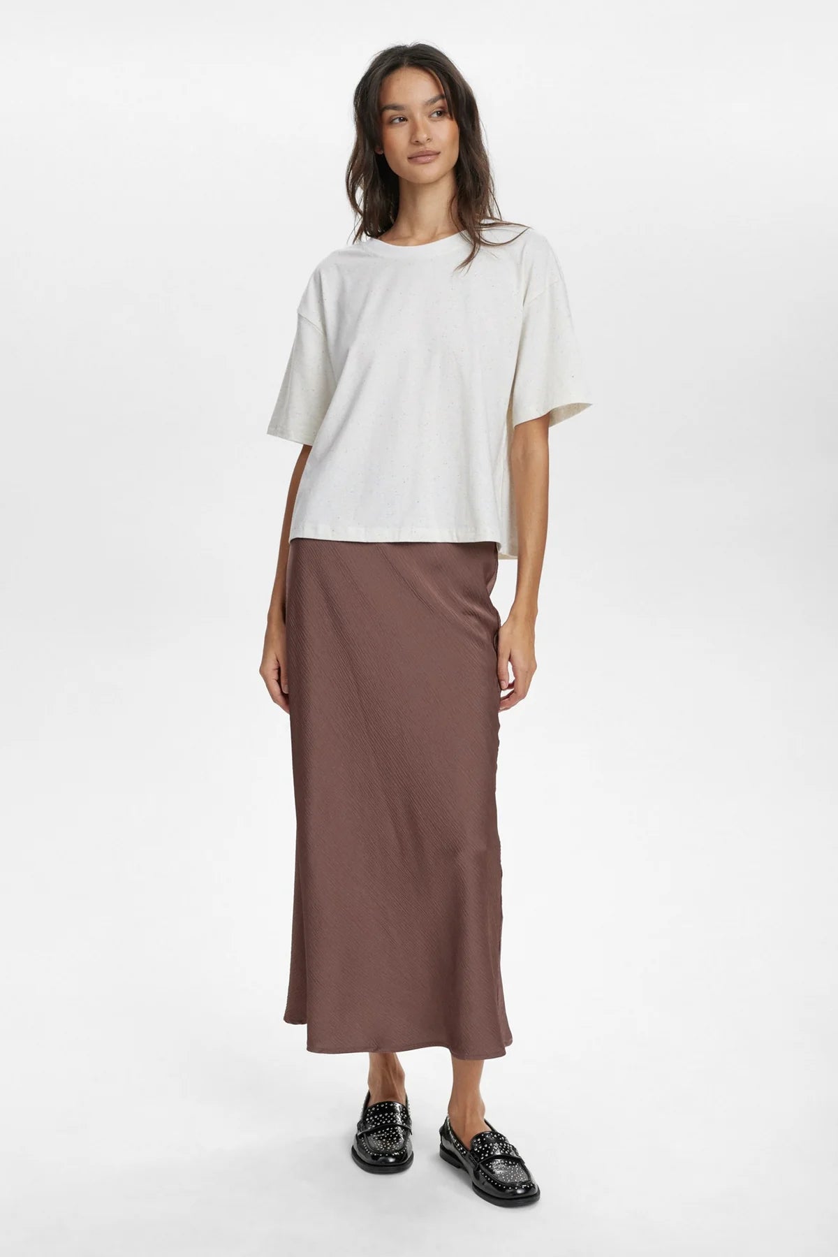 Woman wearing a white top and brown skirt on a white background