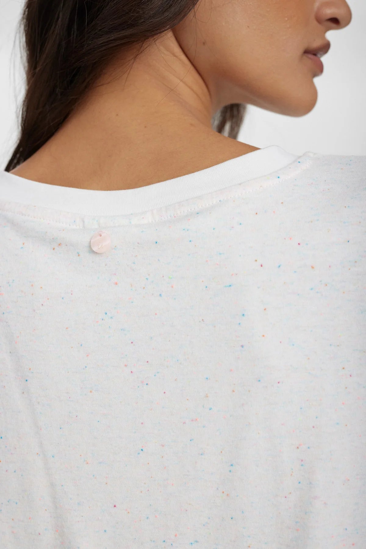 Close-up of a person wearing a white textured shirt with buttons.