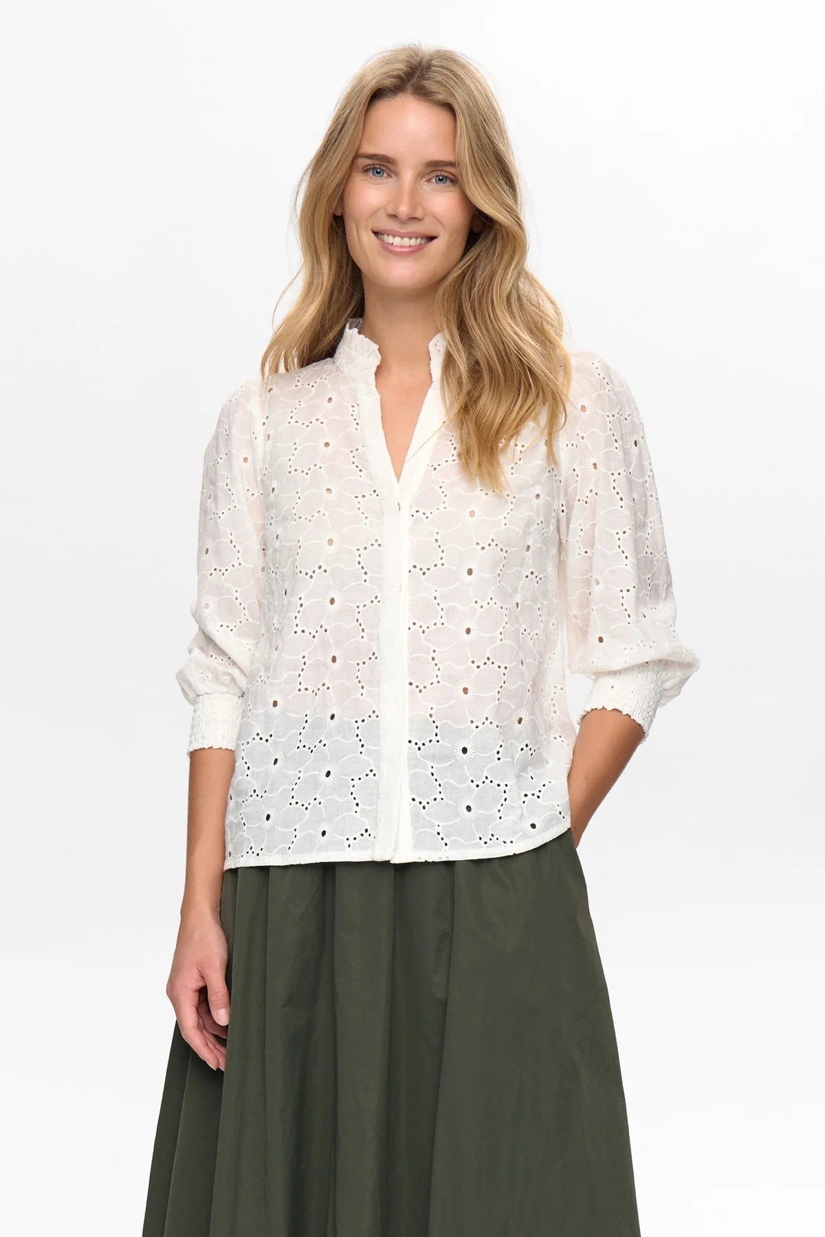 Woman wearing a white lace blouse and green pants on a white background