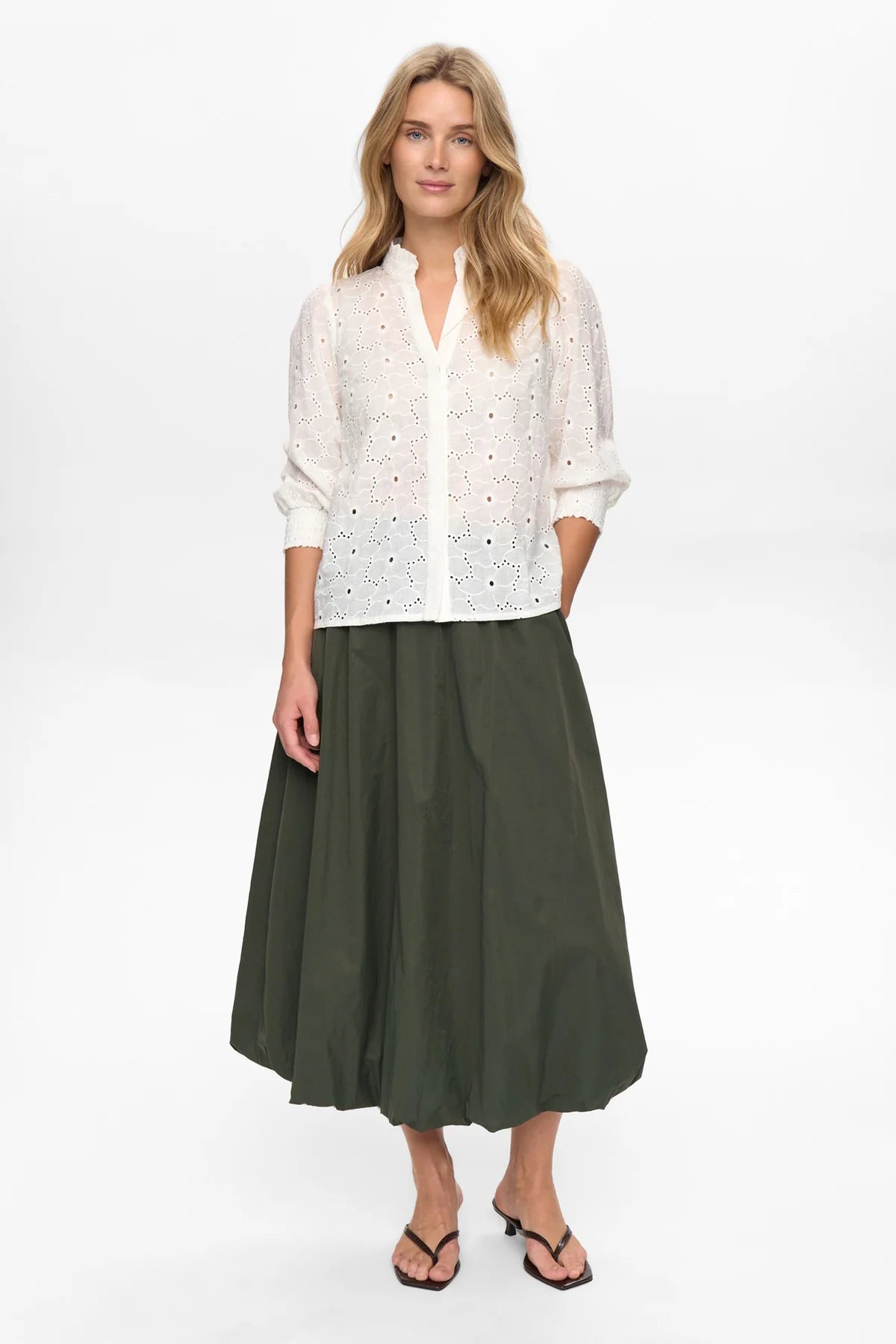 Woman wearing a white blouse and green skirt on a white background