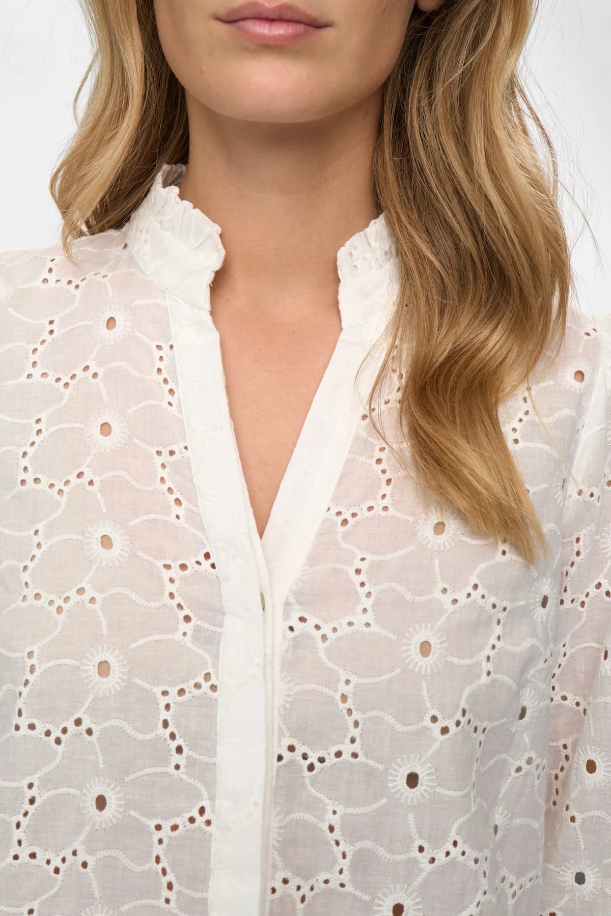 Close-up of a person wearing a white lace blouse with a blurred background