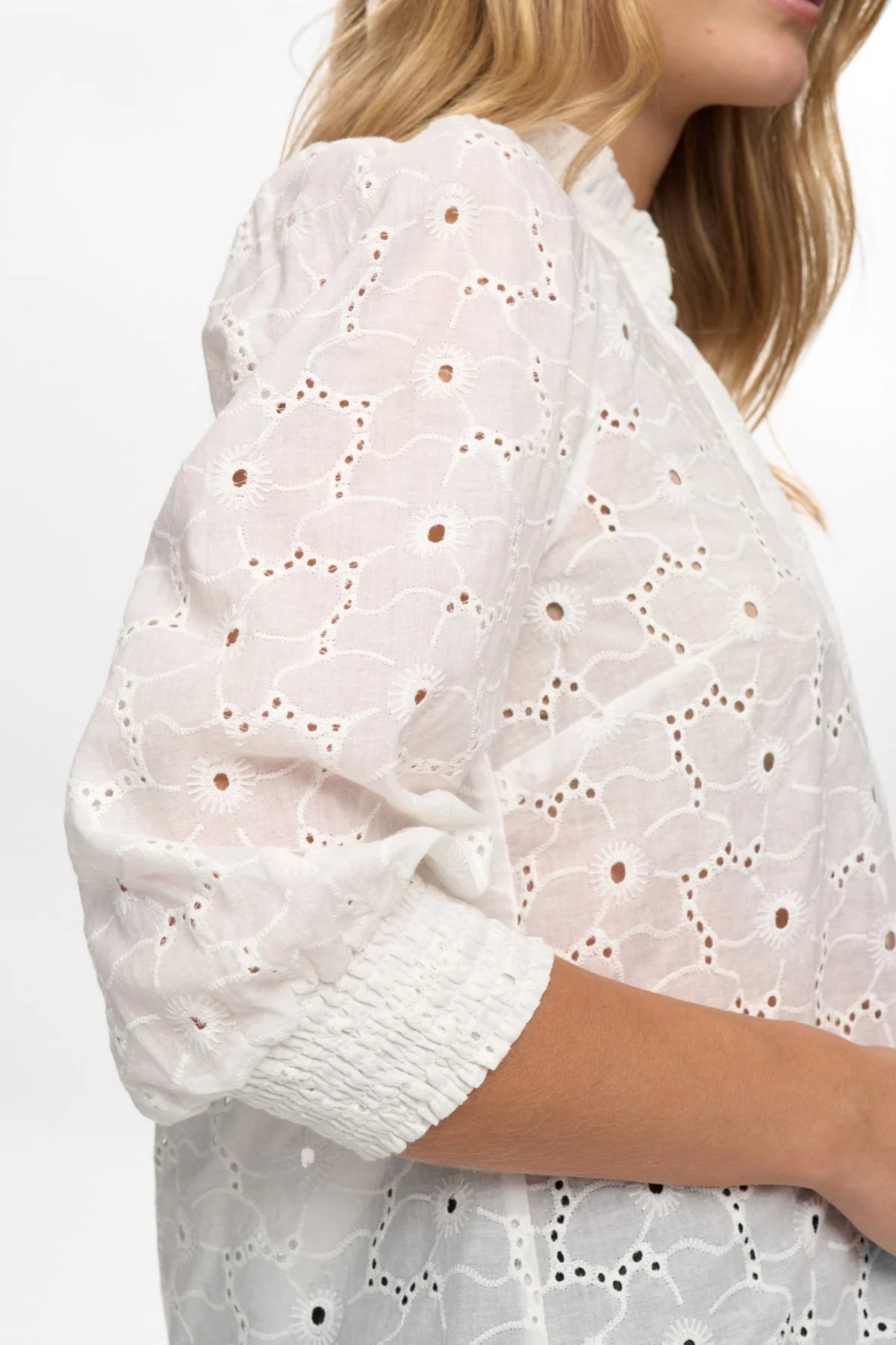 White lace top worn by a person on a white background