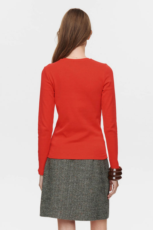 Person wearing a red long-sleeve top and gray skirt on a white background