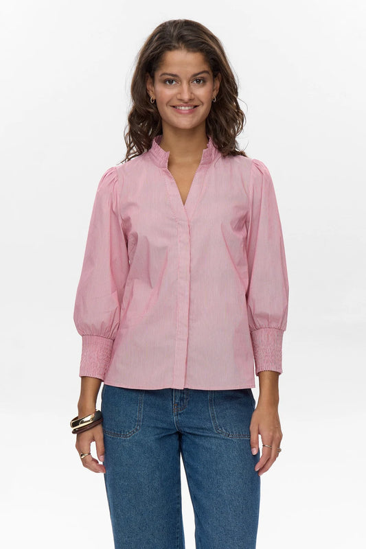 Woman wearing a pink blouse and blue jeans on a white background