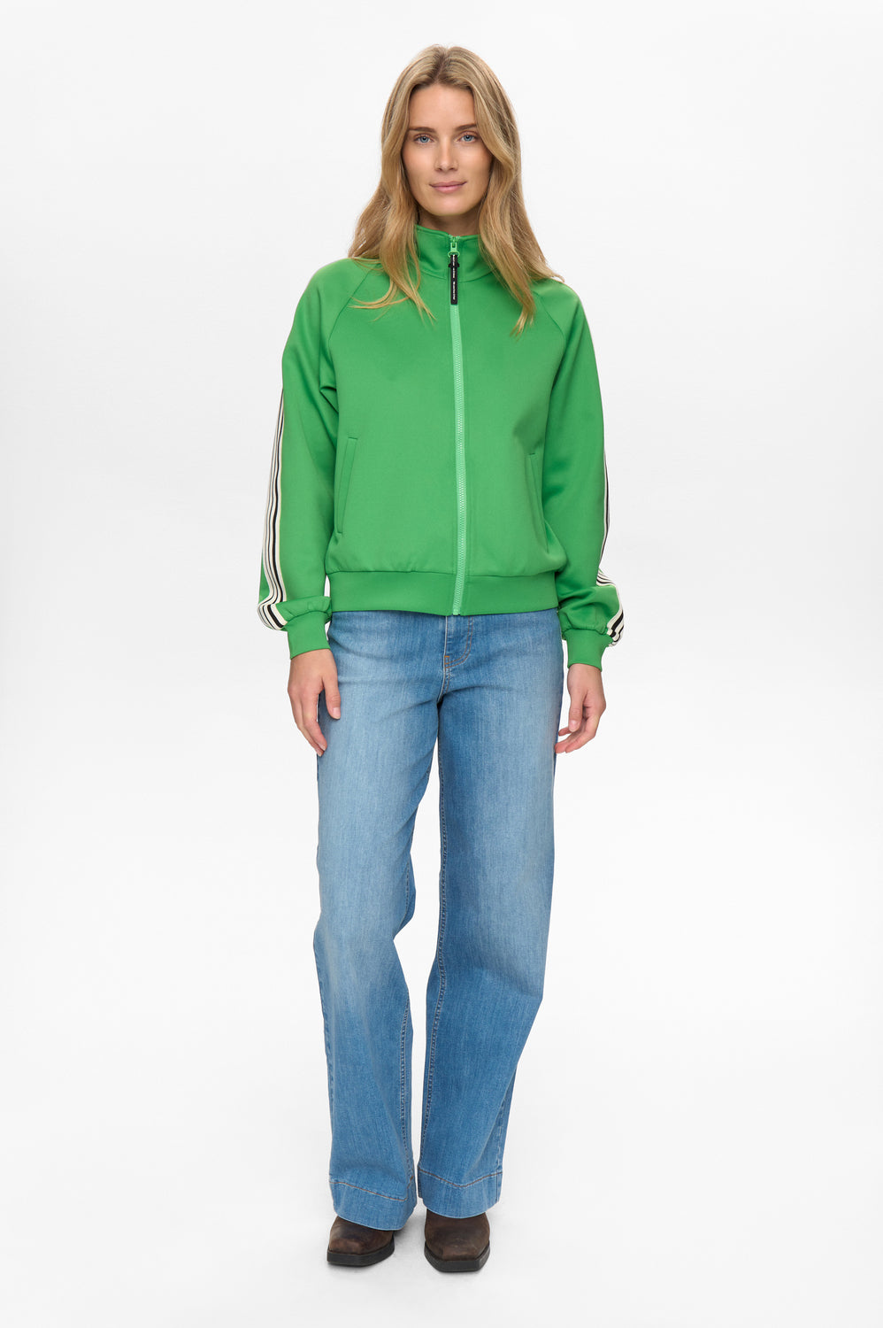 Woman wearing a green jacket and blue jeans on a white background