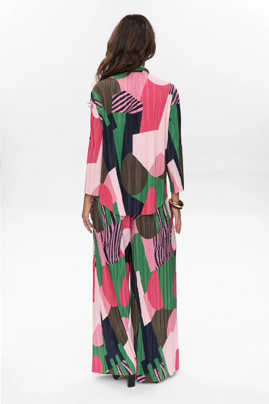 Woman wearing a colorful patterned top and trousers on a white background