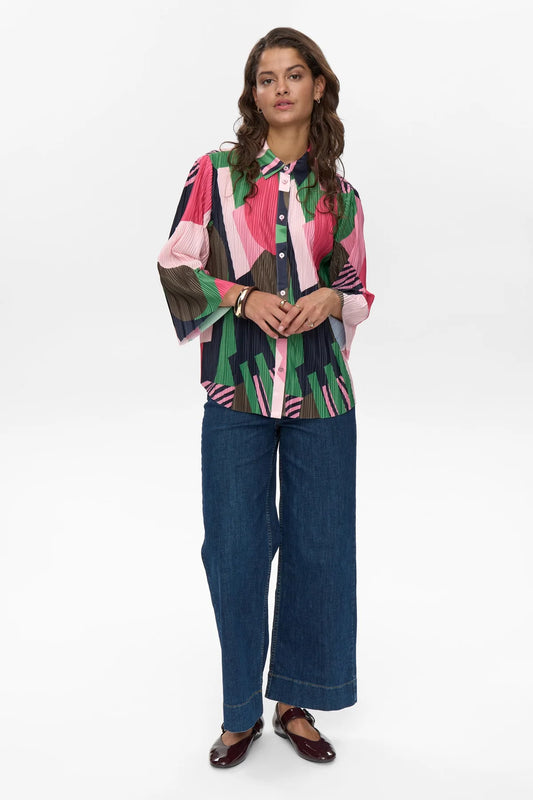 Woman wearing a colorful patterned blouse and blue jeans on a white background