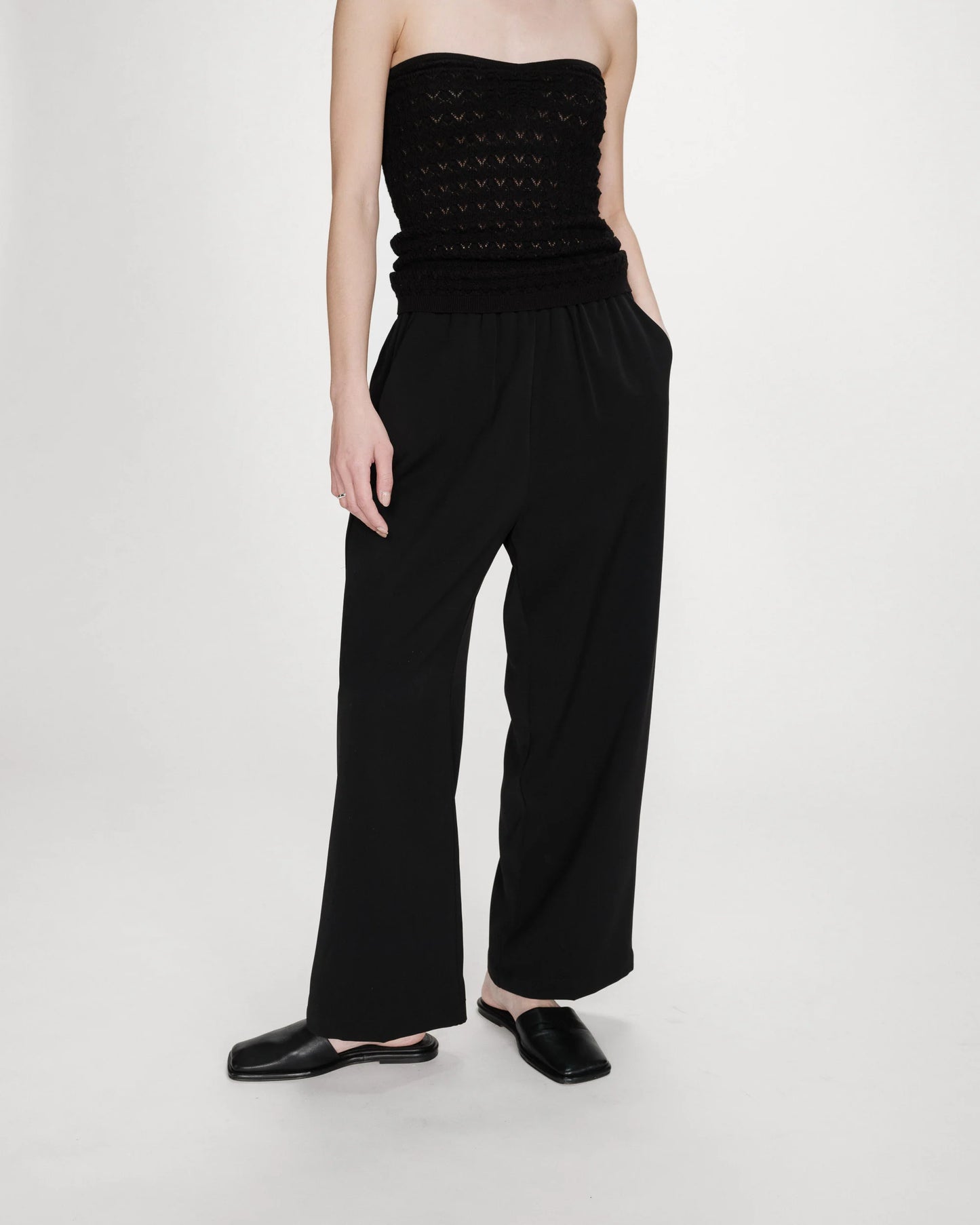 Person wearing a black strapless top and wide-leg pants on a white background
