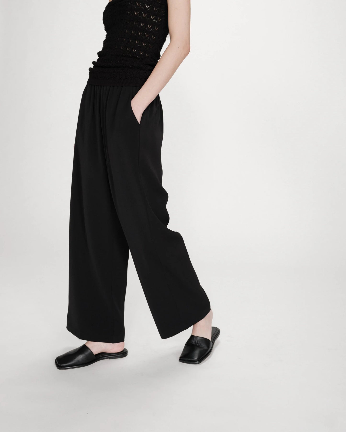 Person wearing black wide-leg pants and a black top on a white background