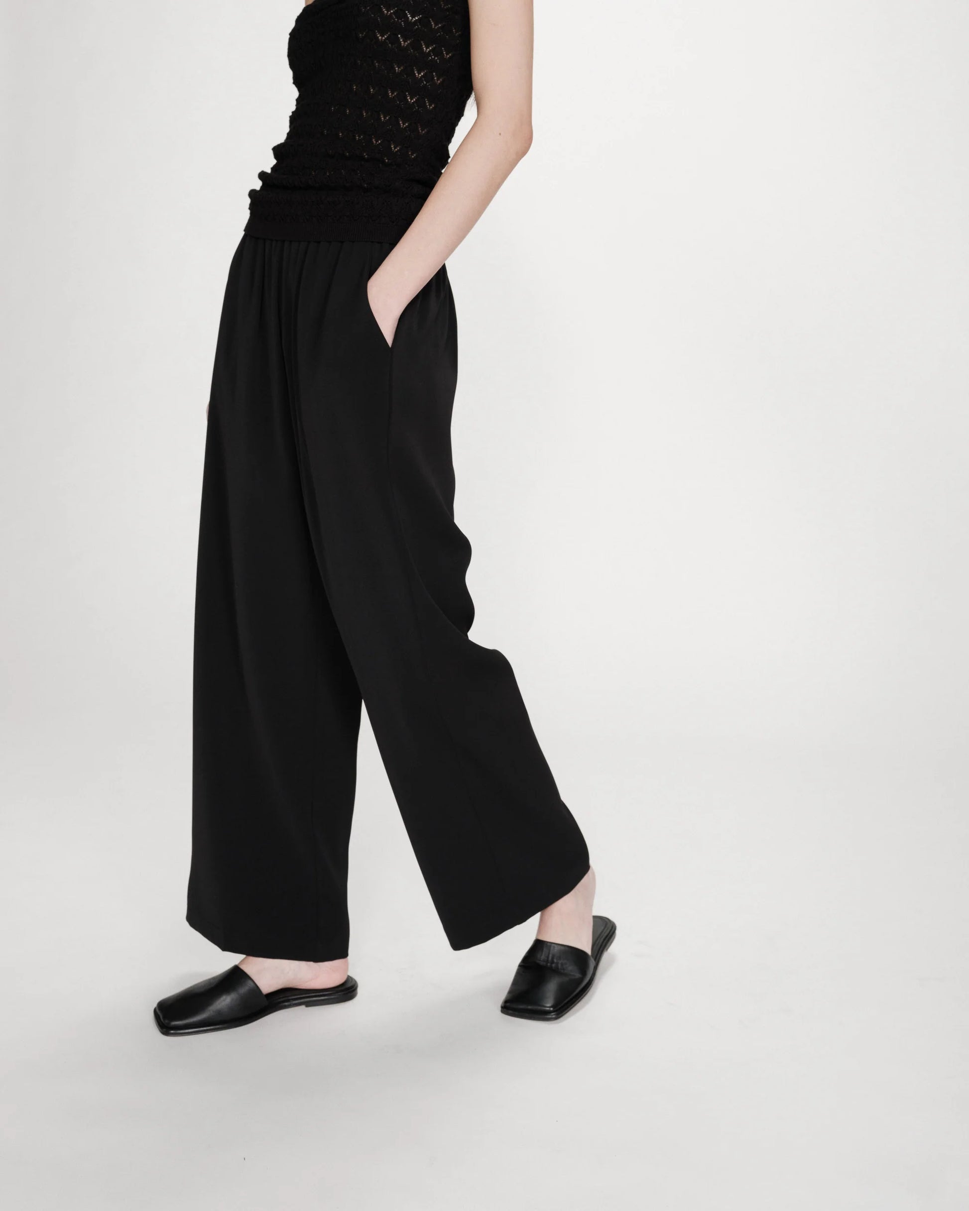 Person wearing black wide-leg pants and a black top on a white background