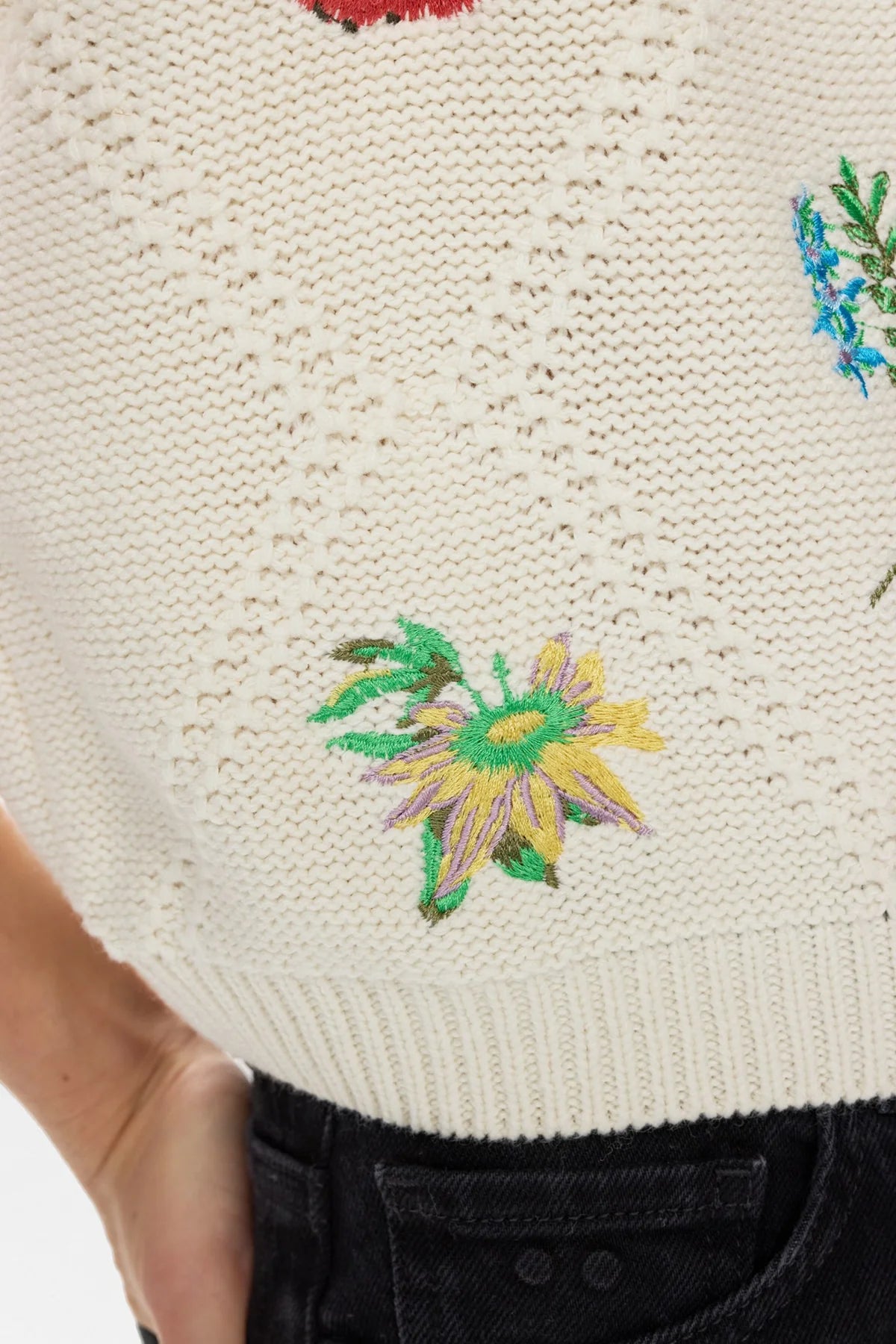 Close-up of a textured fabric with embroidered floral designs on a neutral background