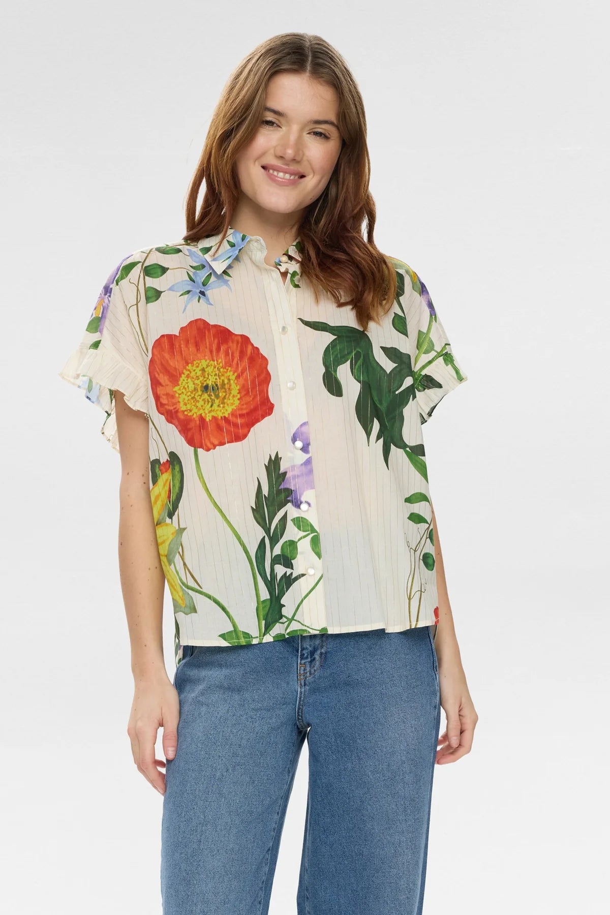 Woman wearing a Floral short sleeve blouse with floral detail with blue jeans on a white background