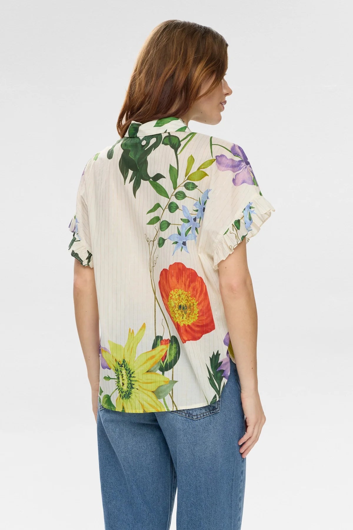 Woman wearing a Floral short sleeve blouse with floral detail with blue jeans on a white background