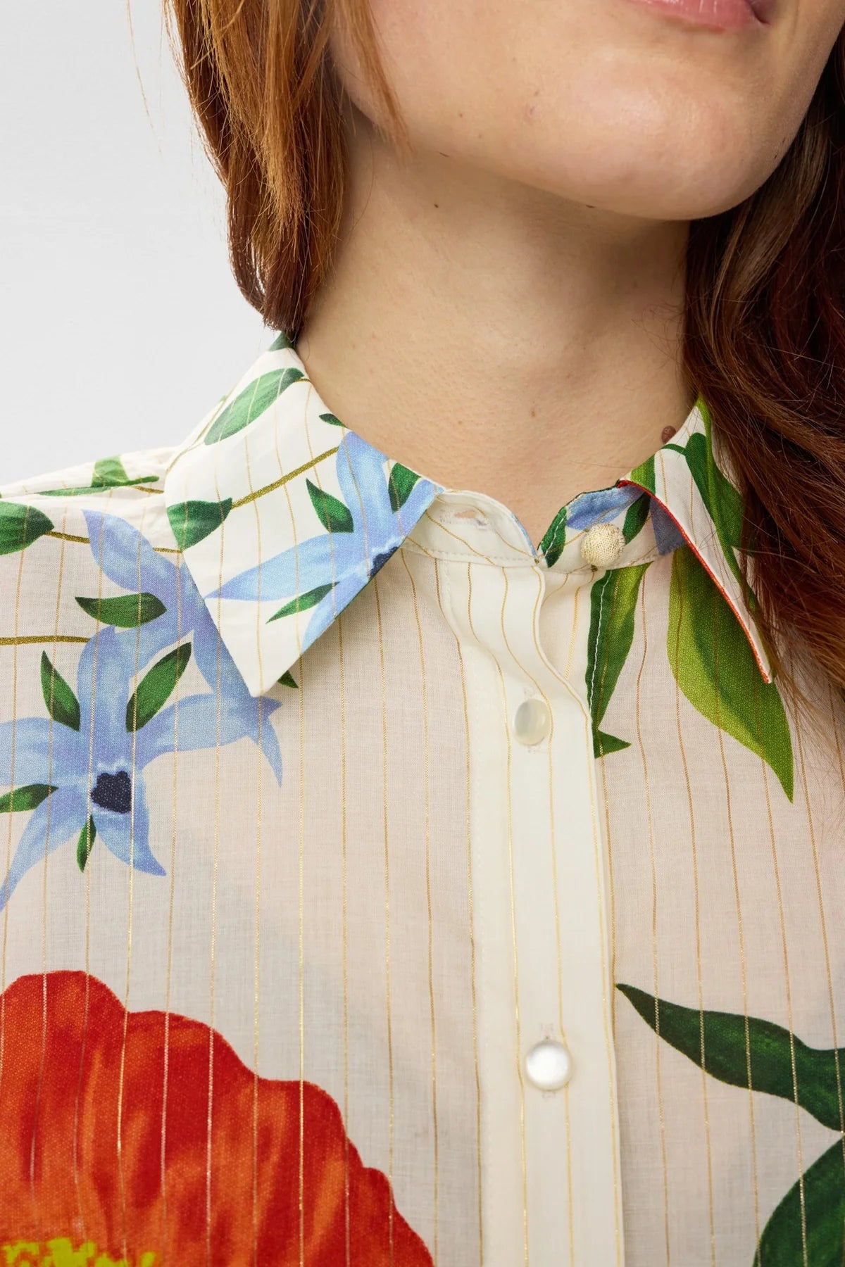 Woman wearing a Floral short sleeve blouse with floral detail with blue jeans on a white background