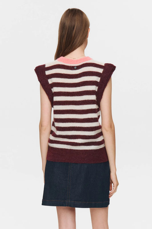 Woman wearing a striped sleeveless top and denim skirt on a plain background