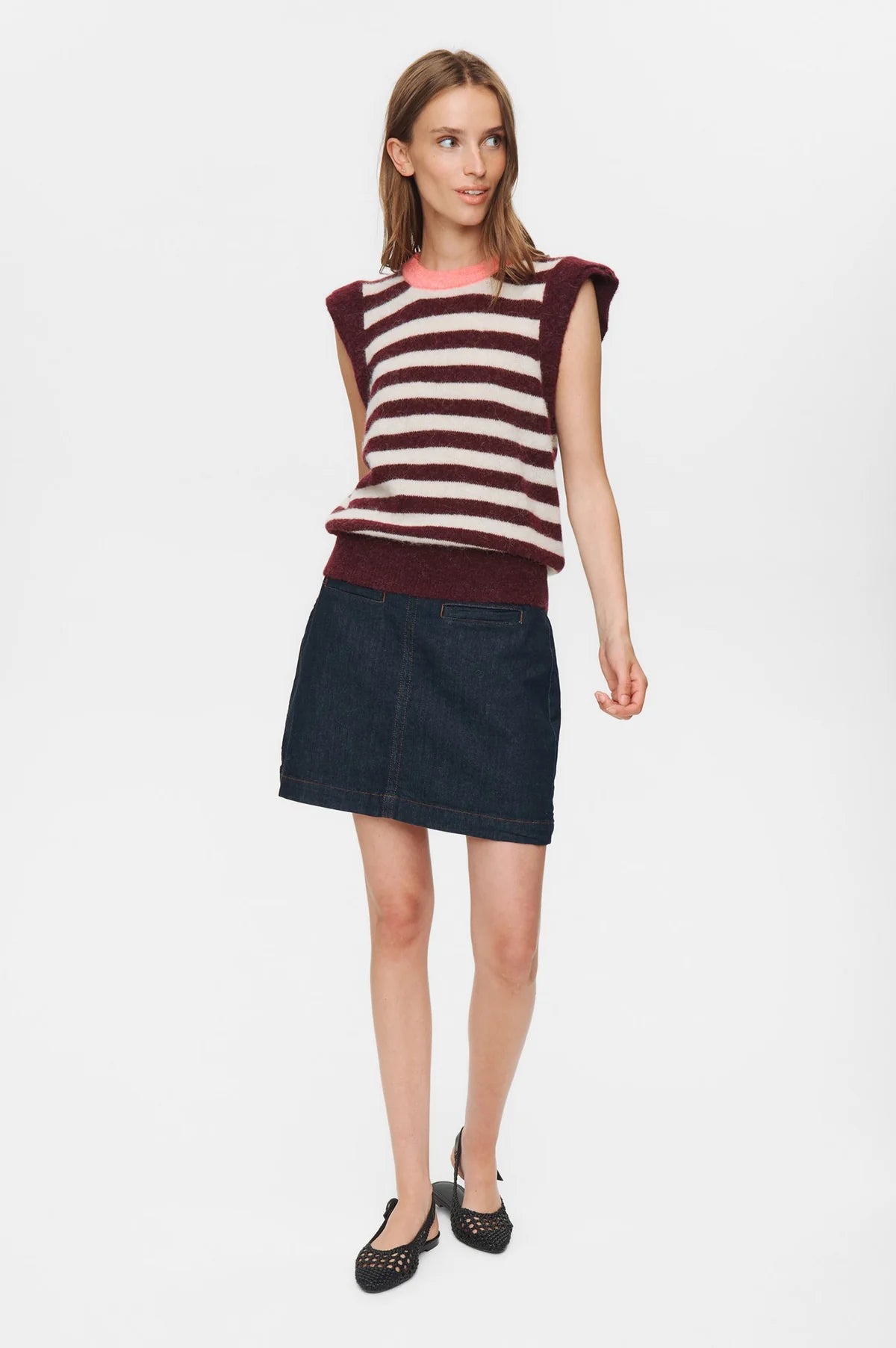 Woman wearing a striped sleeveless top and denim skirt on a white background