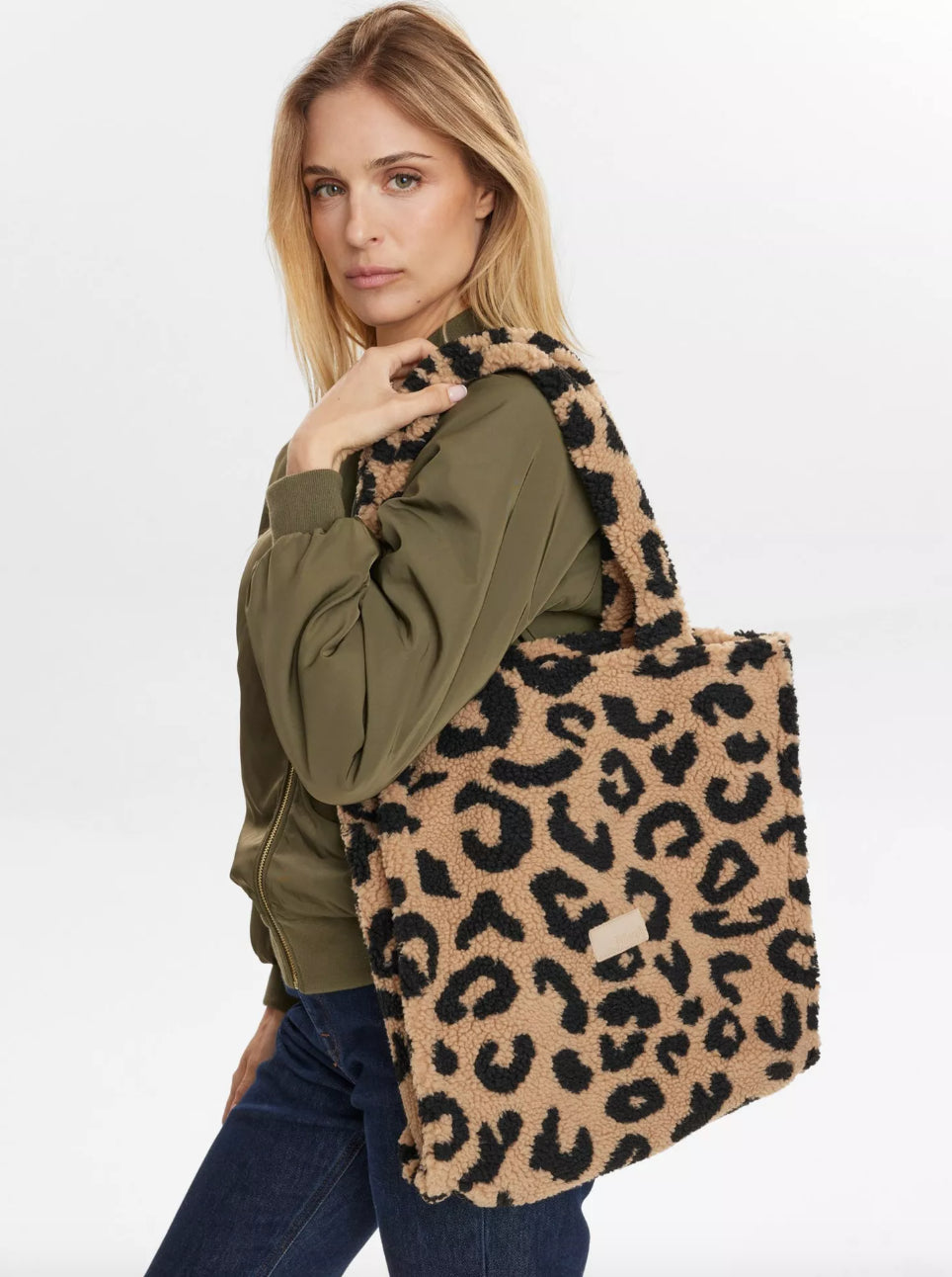 Woman holding a leopard print tote bag against a white background