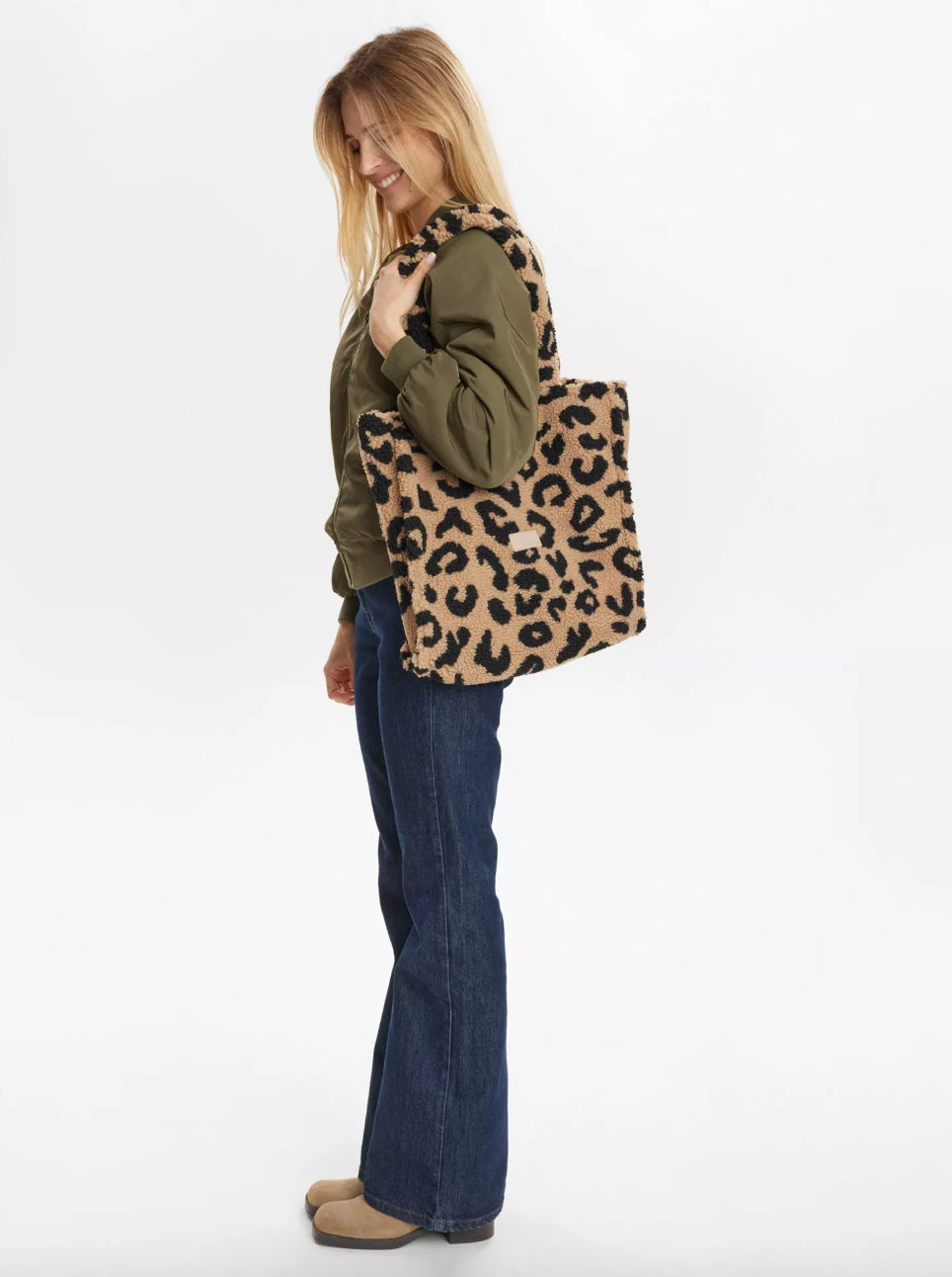 Person holding a leopard print tote bag on a white background