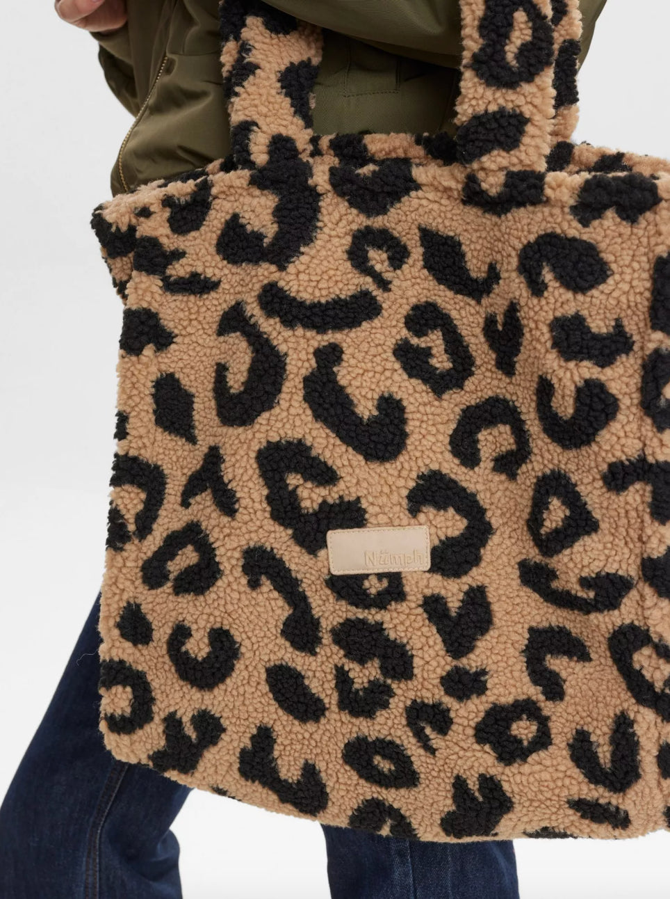 Leopard print tote bag held by a person against a white background