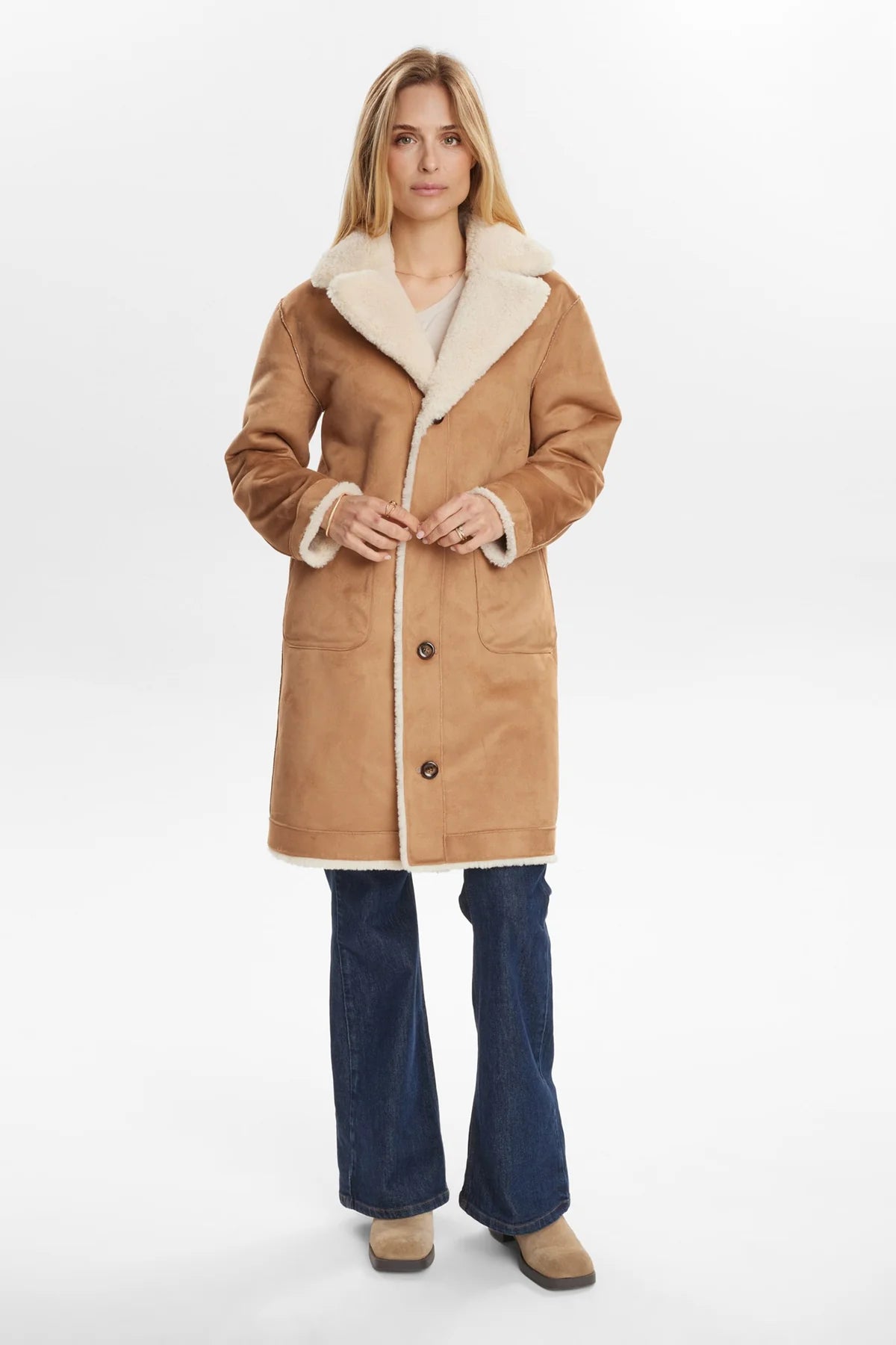 Woman wearing a tan coat with white fur lining on a white background