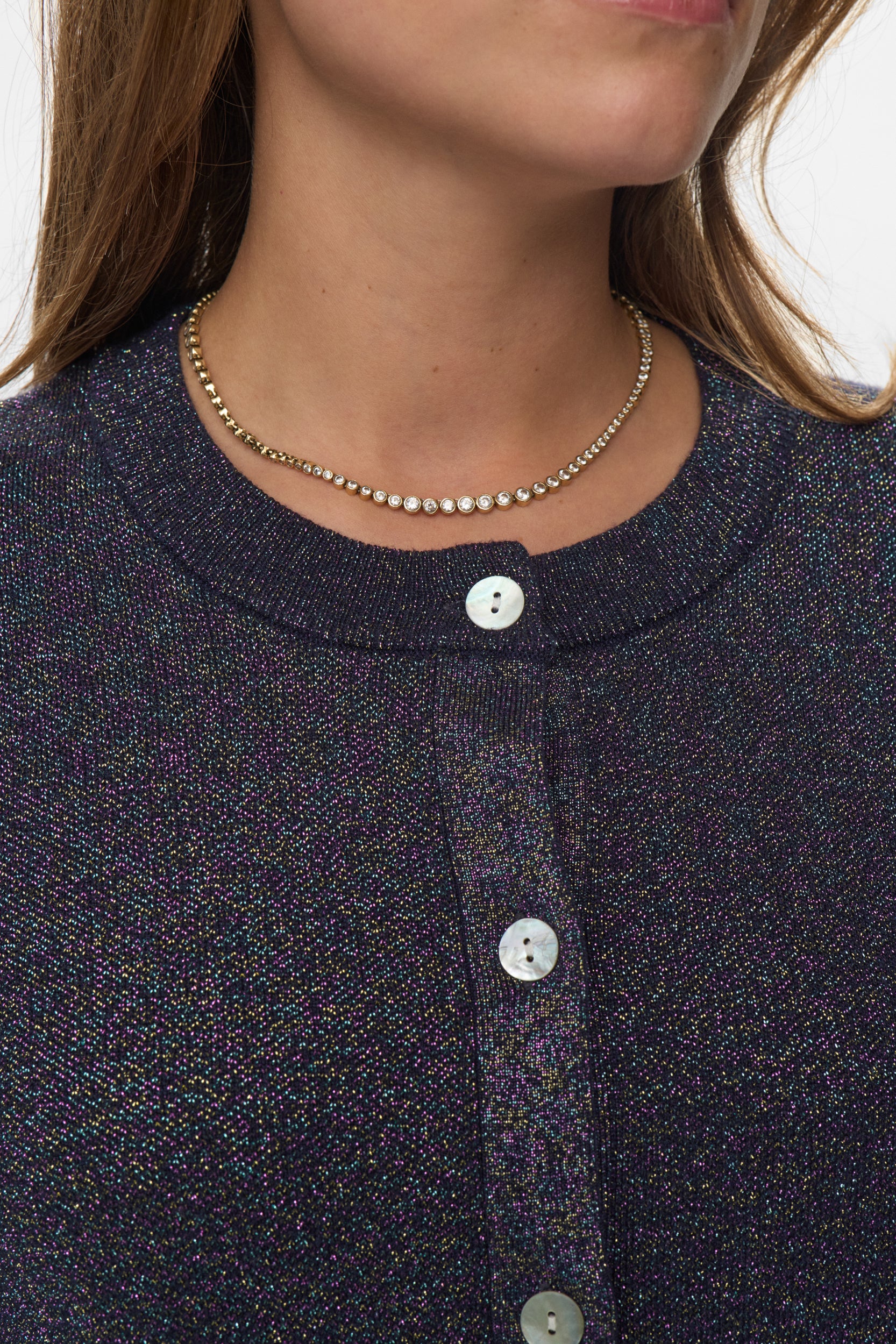 Close-up of a person wearing a dark blue textured shirt with buttons and a necklace.
