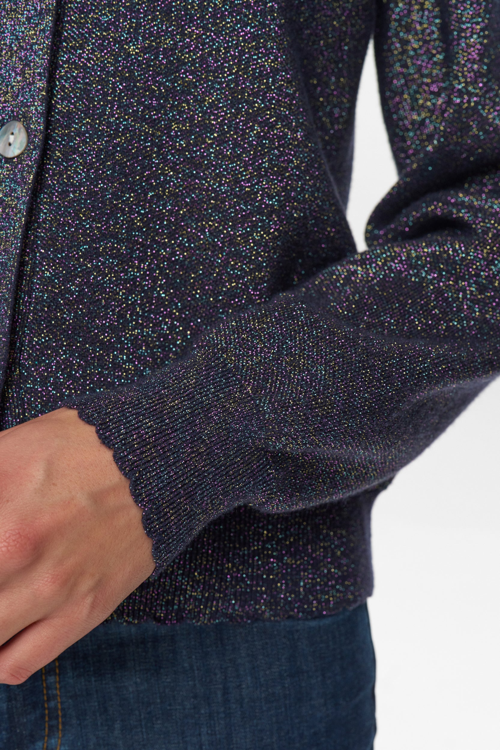 Close-up of a person wearing a dark blue speckled cardigan on a white background