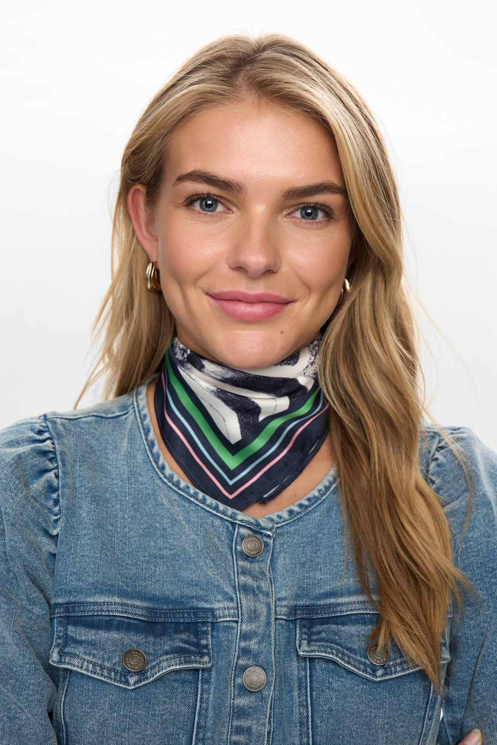 Woman wearing a denim jacket and colorful scarf on a white background