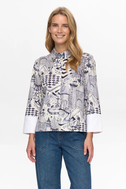 Woman wearing a patterned blouse and jeans on a white background
